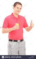 Casual guy holding a glass of orange juice and giving thumb up isolated CX98H0