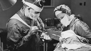 A surgeon using a brace and bit to drill into a patient's skull before performing a lobotomy, at a mental hospital in England, November 1946.