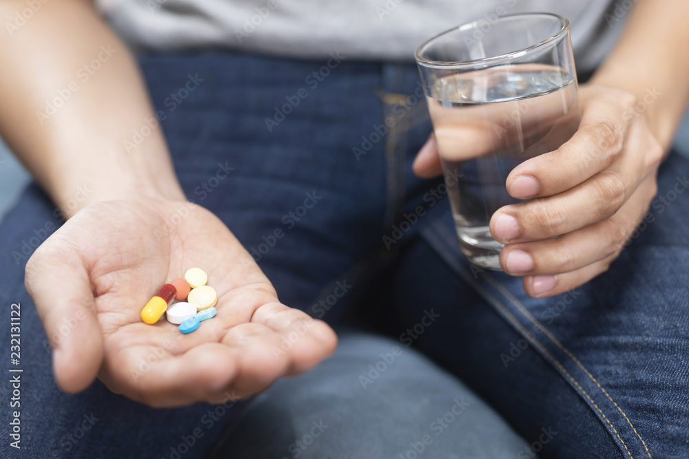 Photo Stock close up hand man taking multiple colors pills take a medicine  in hand holding a cup glass of drinking water. Stop drug use Taking  Medication health care medical concept |