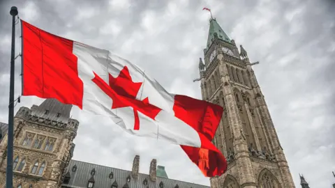 Getty Images A photo of the Canadian flag flying in front of Parliament Hill in Ottawa, Canada.