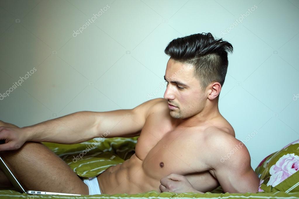 Sexy man in bed with laptop — Stock Photo © Tverdohlib.com #109069414