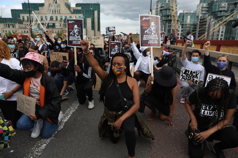 Protesters from a Black Lives Matter rally take a knee at Vauxhall Bridge