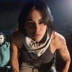 This may contain: an image of a woman with tattoos on her arms and chest sitting at a table