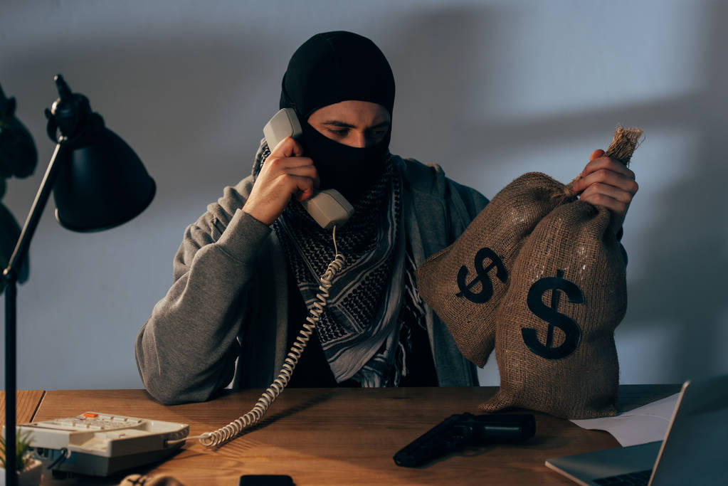 stock-photo-terrorist-mask-holding-bags-money