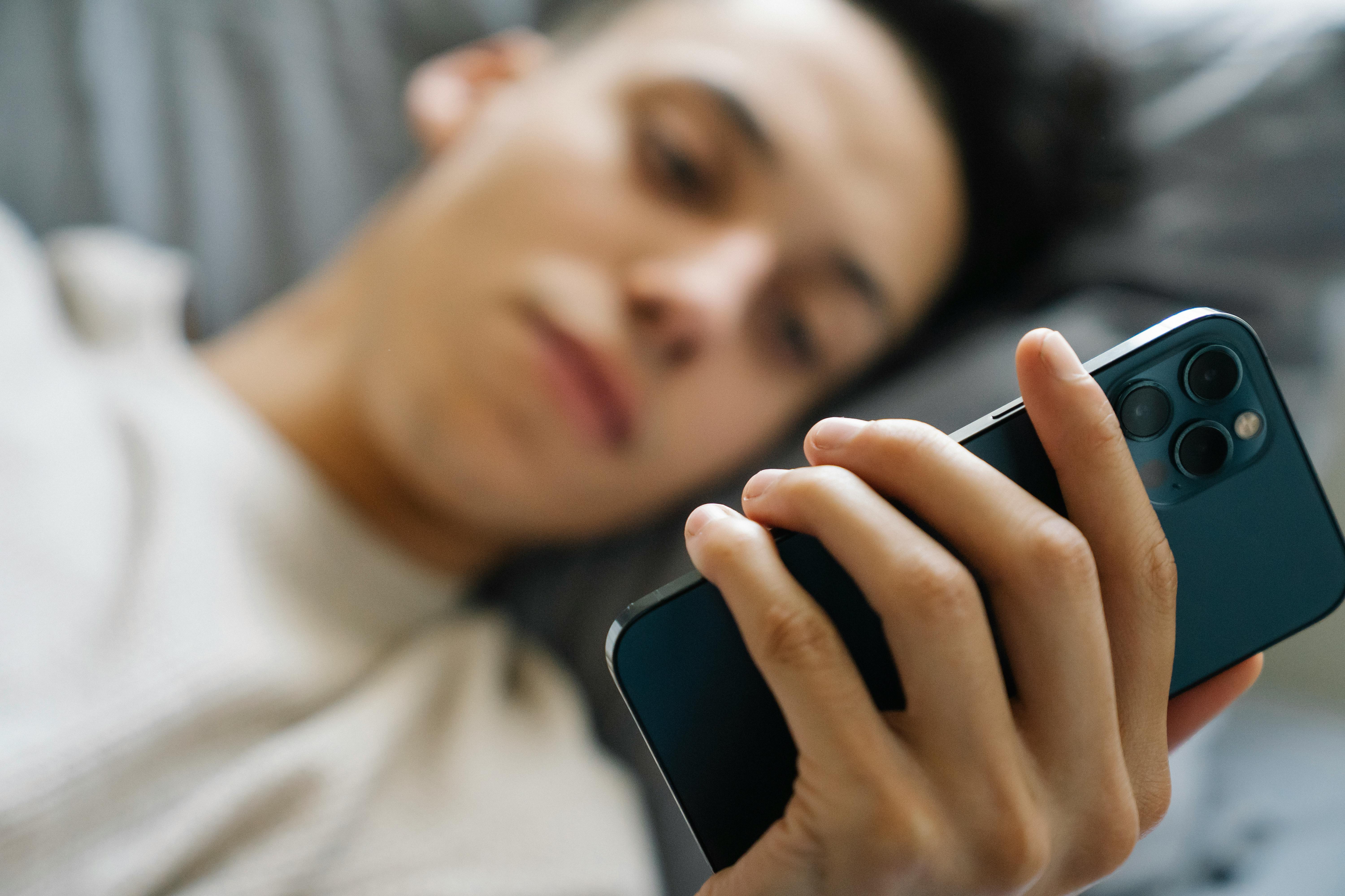 Man lying on the couch looking at his smartphone.