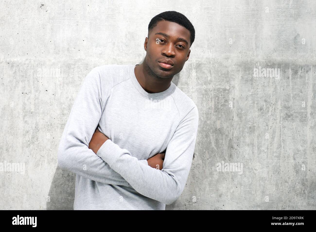 portrait-of-cool-young-black-man-posing-with-arms-crossed-against-gray-wall-2D97XRK.jpg