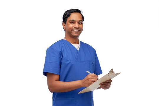 healthcare, profession and medicine concept - happy smiling indian doctor  or male nurse in blue uniform writing medical report on clipboard over  white background Stock Photo | Adobe Stock