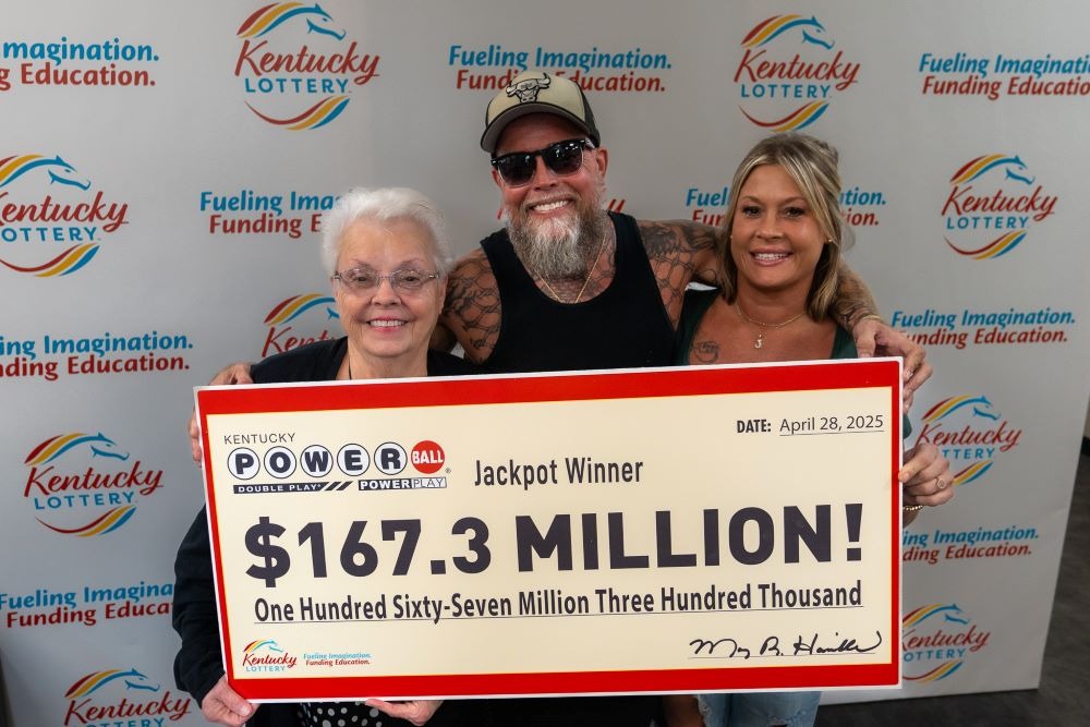 Three lottery winners holding a $167.3 million Powerball check.