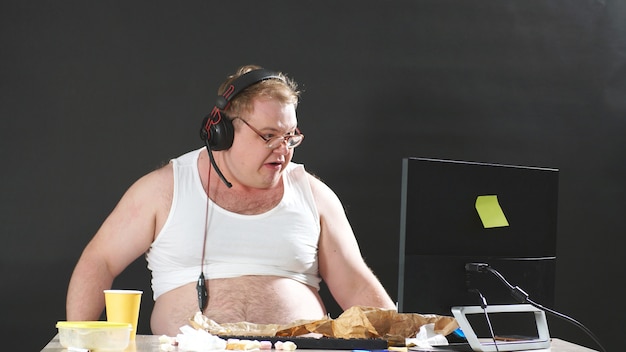 fat-man-with-glasses-headphones-sitting-table-eating-playing-pc-game-home-self-isolation-quarantine_186451-485.jpg