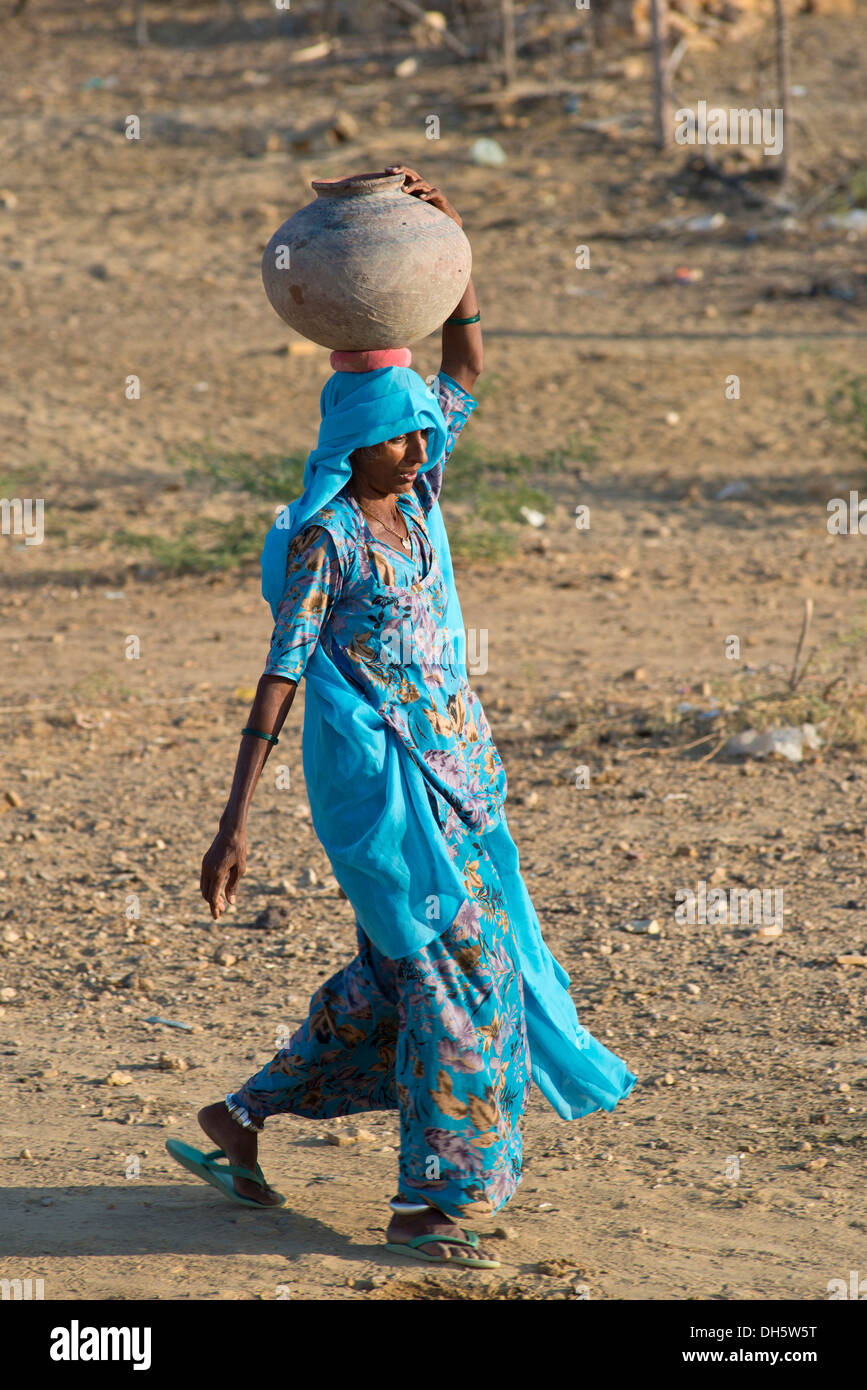 indian-woman-wearing-a-light-blue-sari-carrying-a-clay-water-jug-on-DH5W5T.jpg