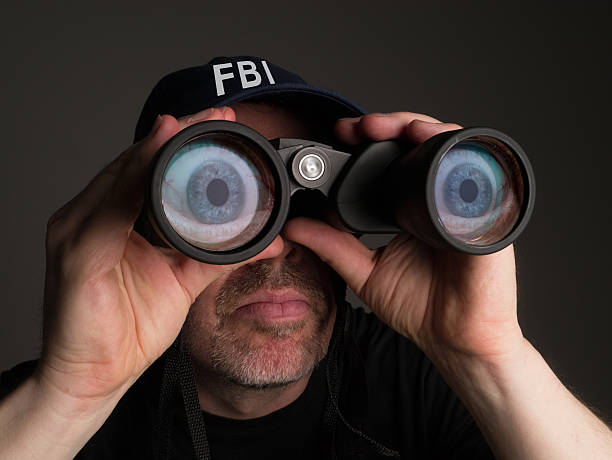 conceptual-image-of-an-fbi-agent-conducting-surveillance-picture-id511789528