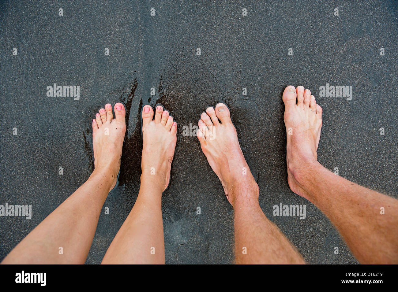 pairs-of-male-and-female-feet-on-black-sand-DT6219.jpg