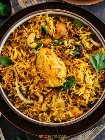 Top shot of chicken biryani in black bowl with forks on the side
