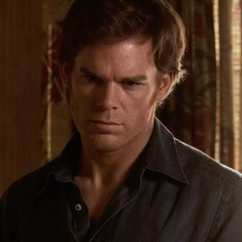 This may contain: a man in a black shirt looking at the camera with an intense look on his face