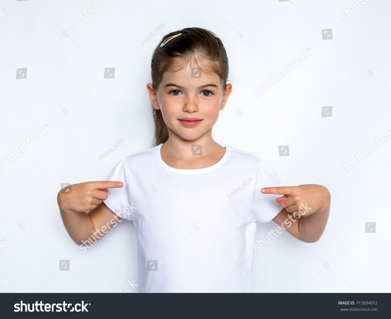 stock-photo-t-shirt-design-concept-smiling-little-girl-in-blank-white-t-shirt-pointing-at-herself-712834012.jpg
