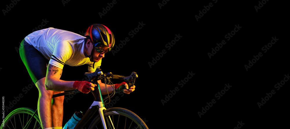 Flyer with male cyclist riding bicycle wearing cycling shorts and  protective helmet isolated on dark background in neon. Concept of sport,  speed, energy Photos | Adobe Stock