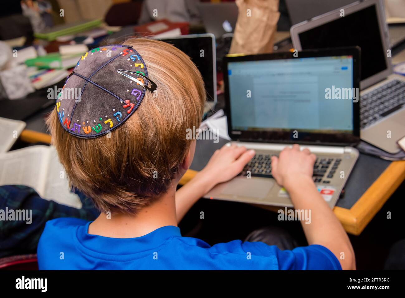 young-jewish-boy-wearing-yarmulke-from-the-back-typing-on-a-keyboard-at-school-2FTR3RC.jpg
