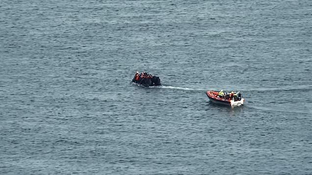 Moment migrant vessel motors away from French coastguard boat