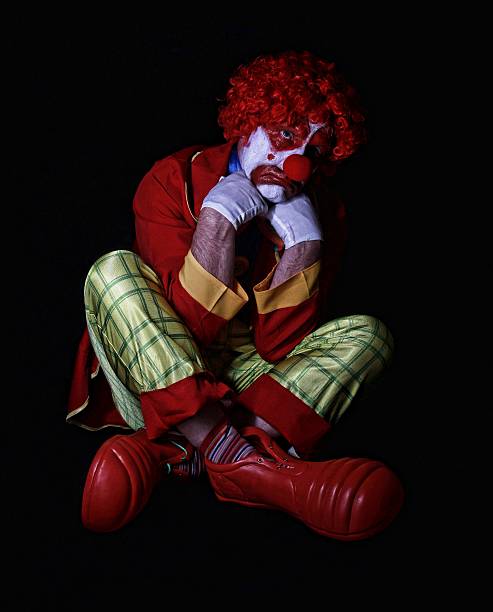 sad-clown-sitting-on-floor-with-legs-crossed-picture-id476454822