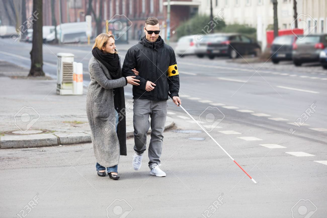 81079238-young-woman-assisting-blind-man-with-white-stick-on-street.jpg