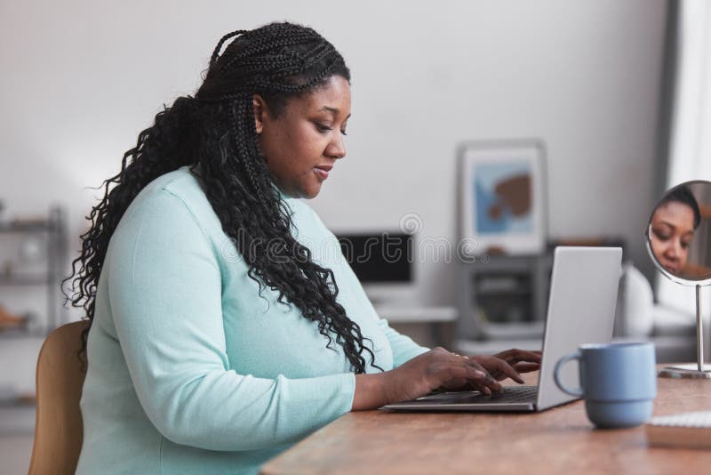 side-view-portrait-curvy-african-american-woman-using-laptop-desk-typing-enjoying-work-home-minimal-210503368.jpg